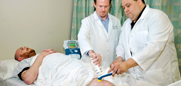 Two physical therapy assistants help a patient.