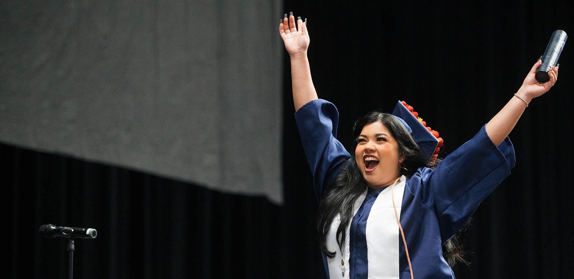 A DMC graduate holding up her arms in triumph