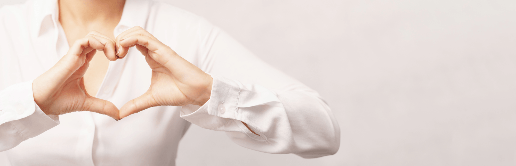 Hands making a heart on beige background