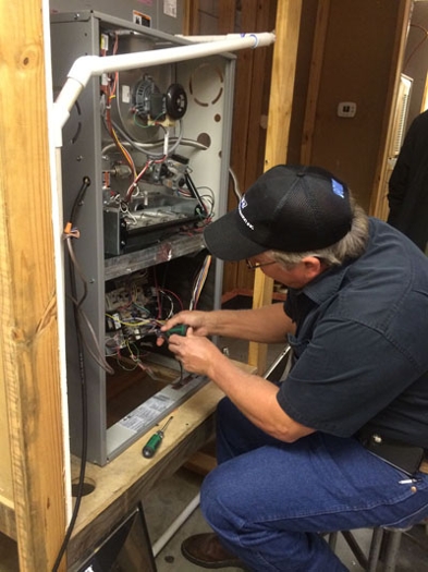 AC technician working on some wiring inside of a circuit box