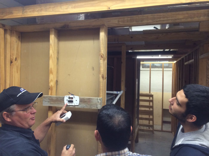 Instructor explaining to two students while showing them the insides of a thermostat