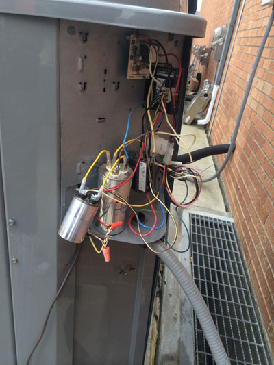 The wiring behind an outdoor air conditioning unit.