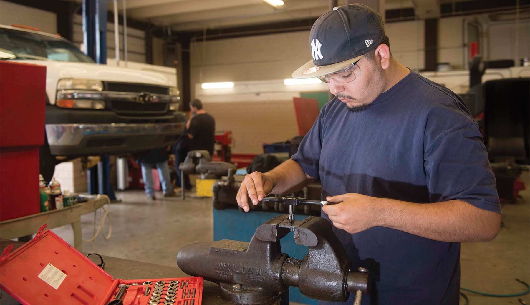 Two Automotive students looking inside of the hood of a car.