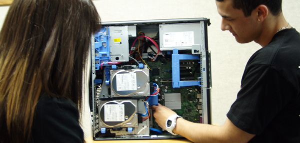 Two computer science students looking at the inside components of a computer.