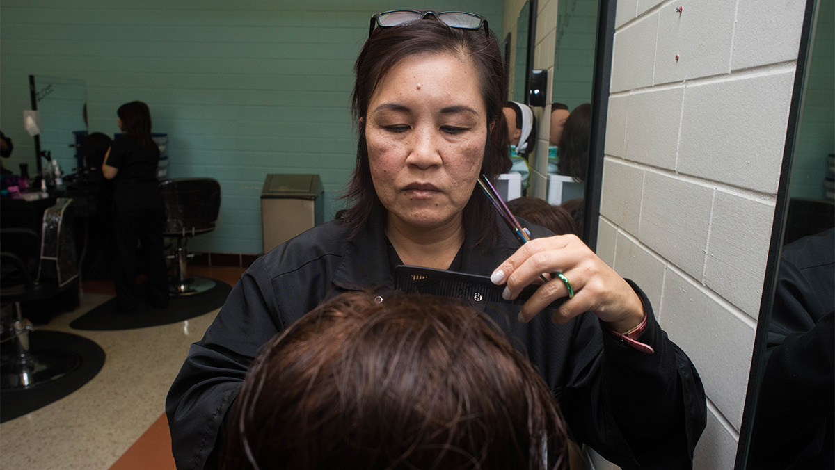 A student styles the hair on a dummy.