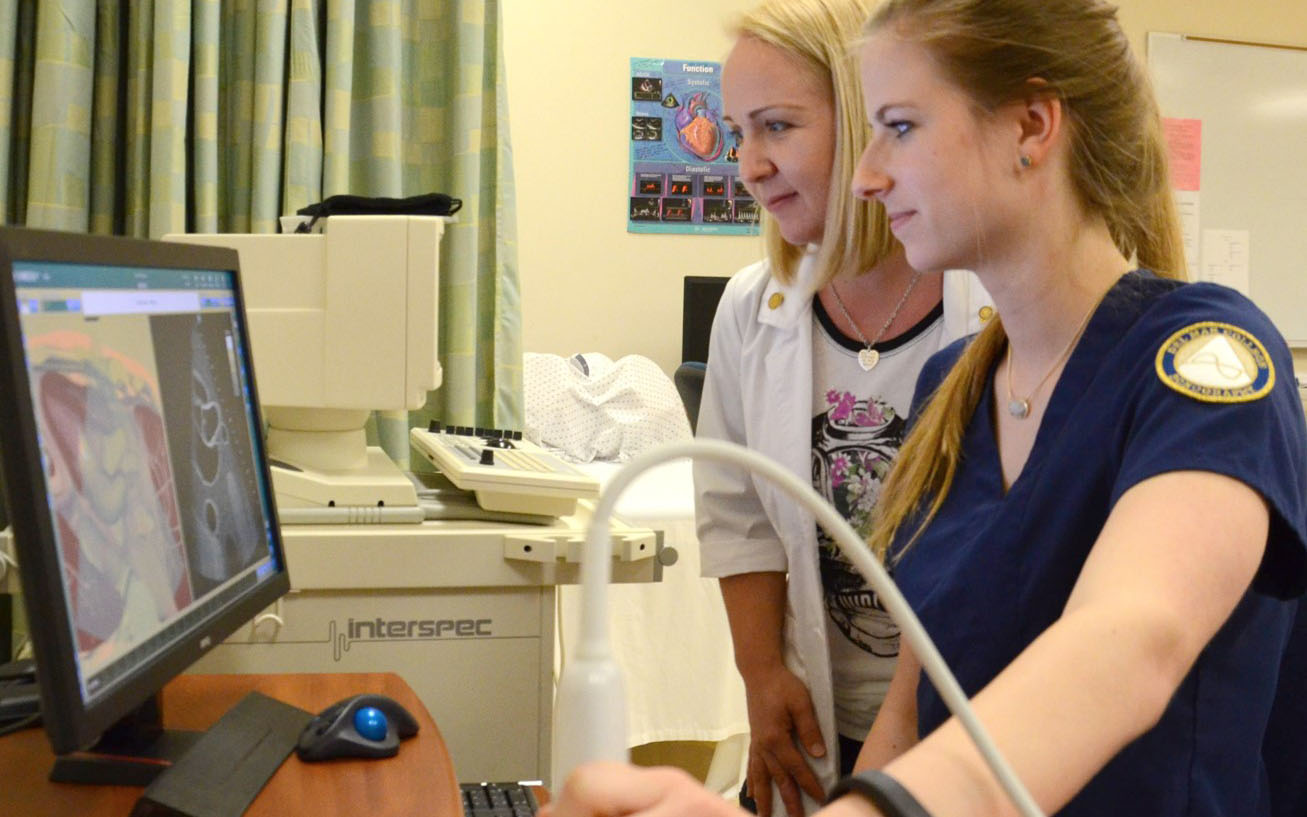 A student examines a patient in the lab.