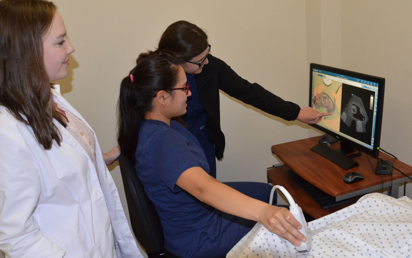 A student examines a patient in the lab.