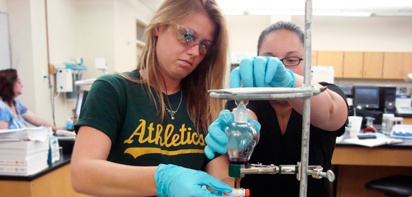 Two students are in the lab performing various lab procedures.