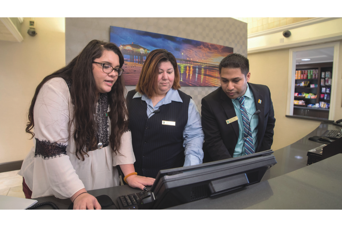 Three hospitality management students at hotel front desk