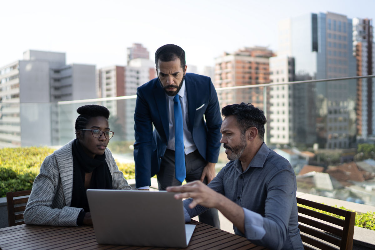 Two business men and a business woman have an outdoor meeting