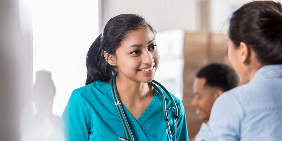 Young woman in medical scrubs assisting a patient