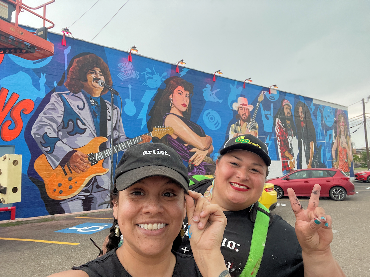 Monica and Maya in front of their artwork on the outside of a building