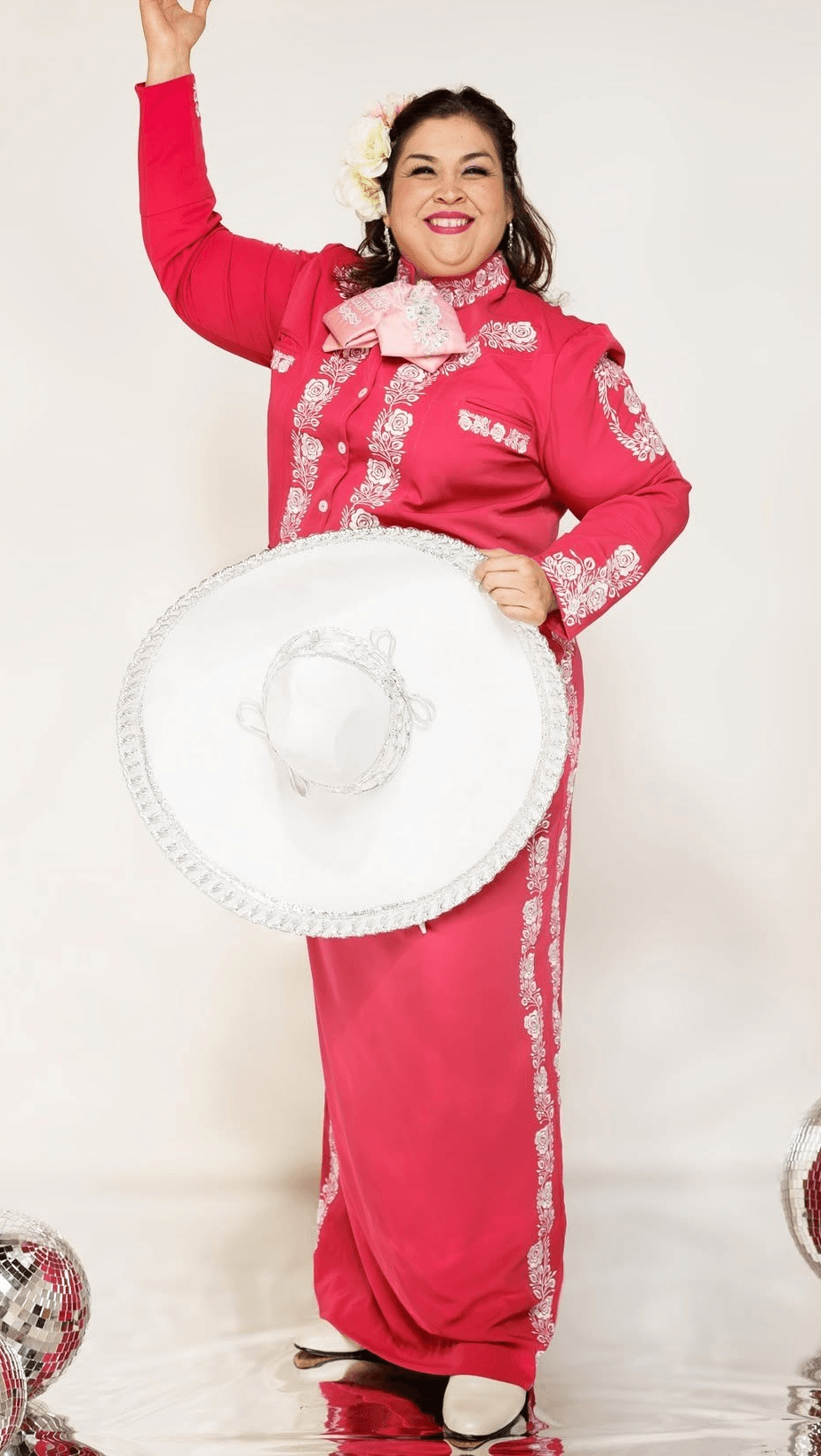 Margaret Rodriguez in a hot pink mariachi outfit holding a white sombrero hat.