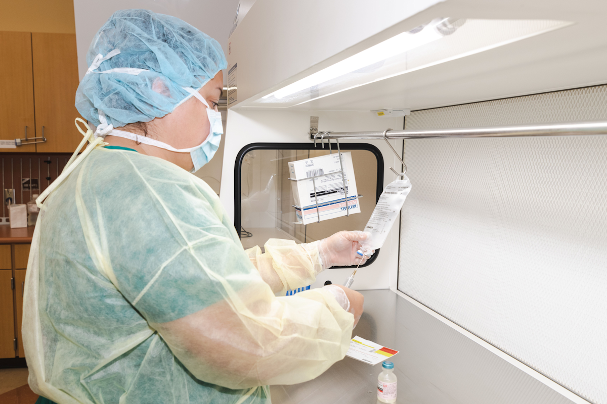 Pharmacy technician injecting iv bags.