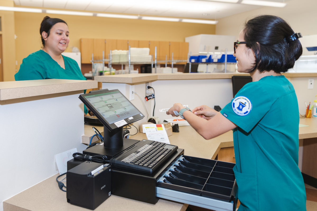 Pharmacy technician using point of sale terminal.