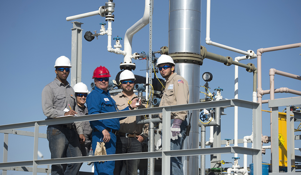 One female and four male students standing on a platform