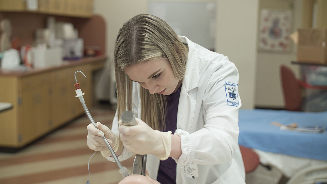 A female student practices techniques using medical equipment