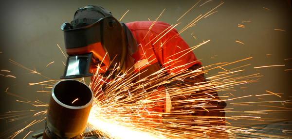 A student welding in the welding shop wearing proper welding equipment.