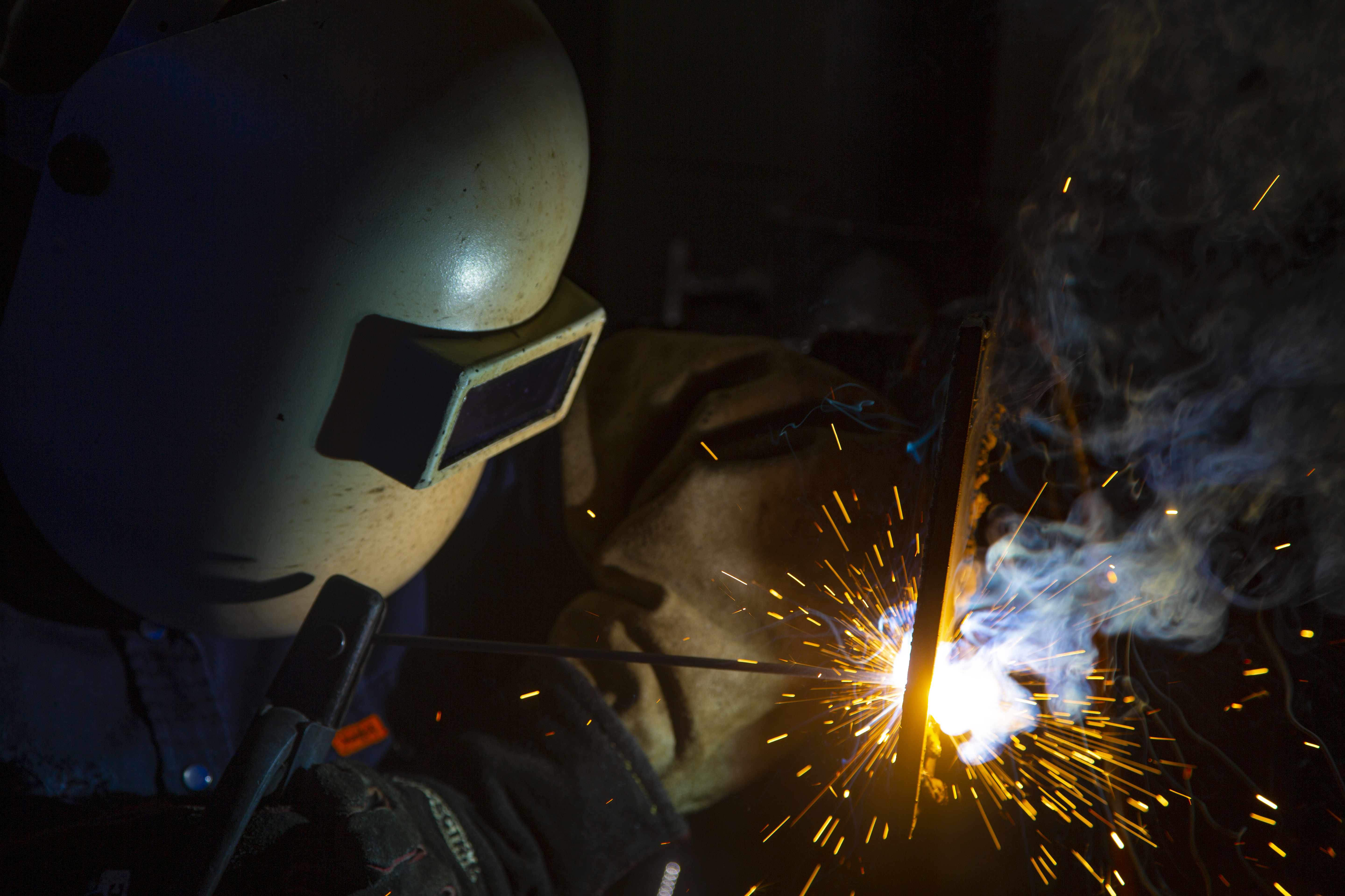 Woman welding a metal bar with sparks flying