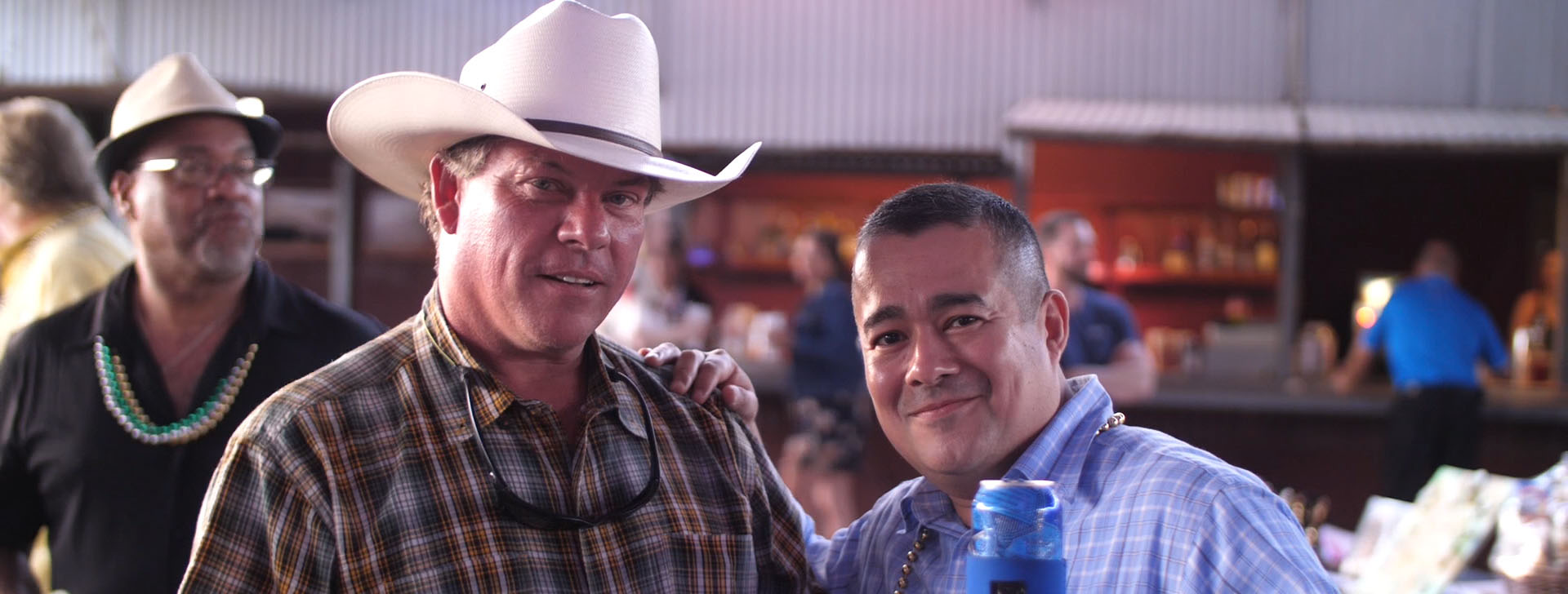 Gentlemen, one in a cowboy hat, enjoy the Crawfish Boil. Cheers!