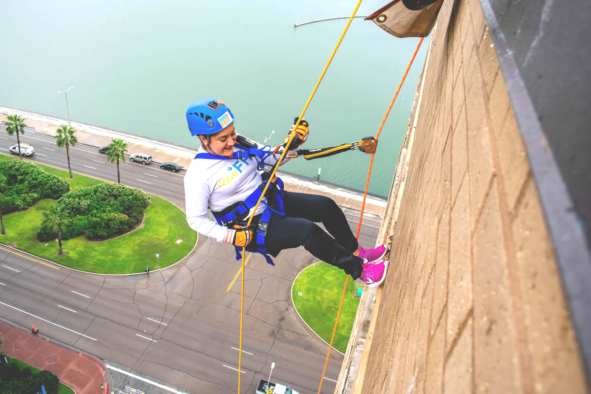 Madi Mendez of Flint Hills Resources rappels off the top of the Holiday Inn Downtown Marina in Corpus Christi, TX
