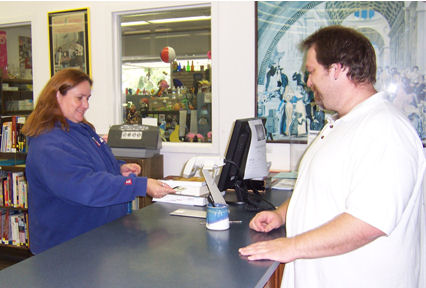 A student checks out books at the White Library Access Services Desk