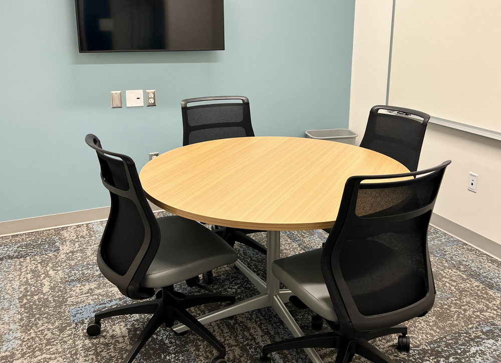 Study room with a table and chairs and a computer screen on the wall