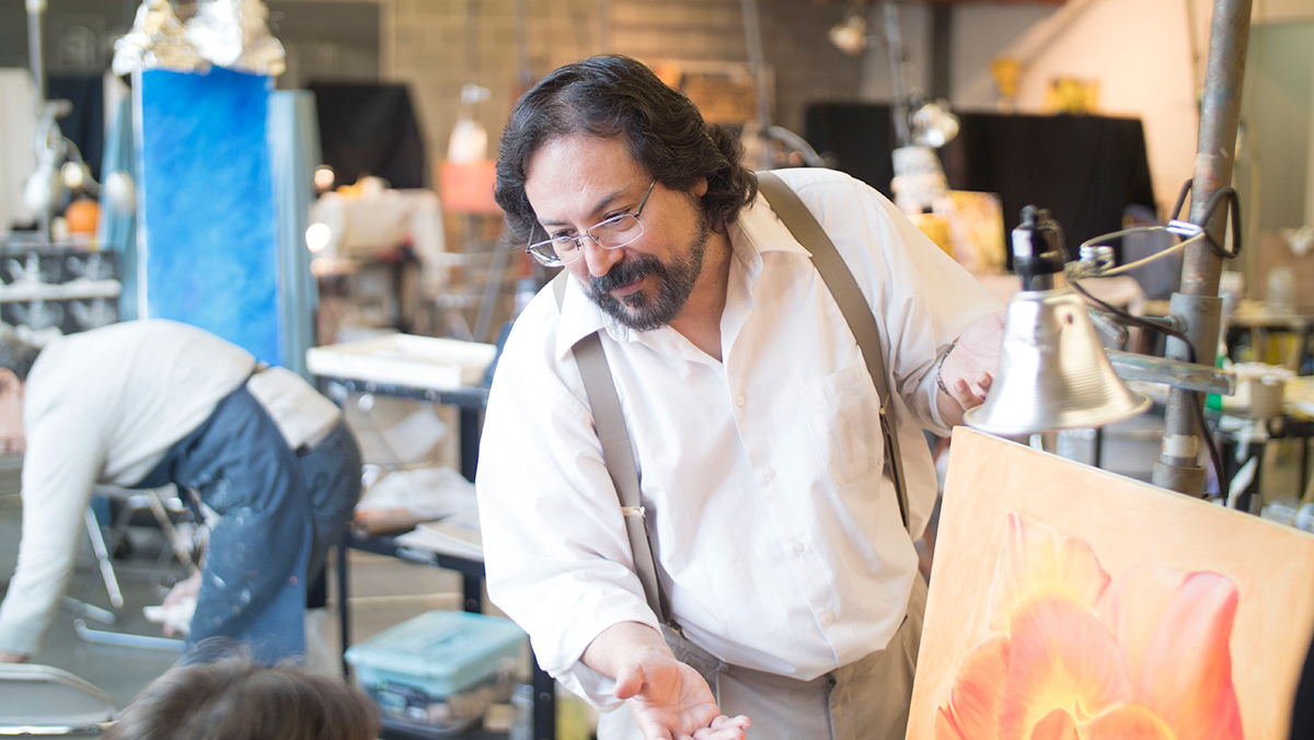 An instructor speaks to a student who is painting