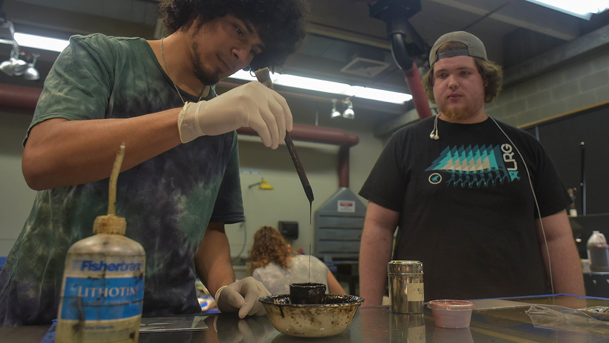 Two male students work together on a project in the studio