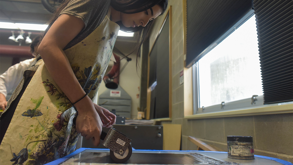 A female printmaking student works on a project