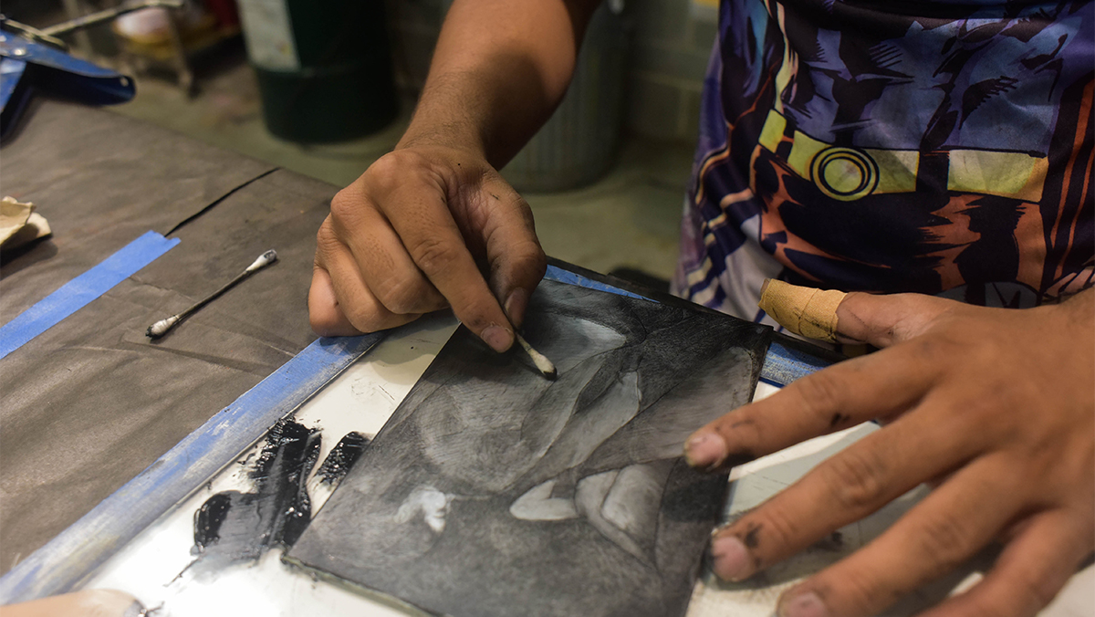 Close up of a student's hands working on a print piece