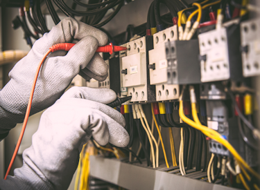 Worker's hands repairing an electrical breaker box
