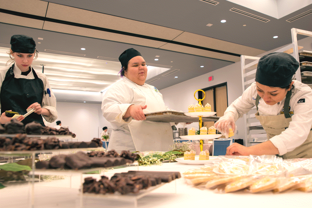 Three culinary arts students preparing food for their class.