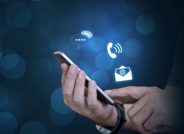 A hand holds a cell phone, with text, phone and email icons floating above