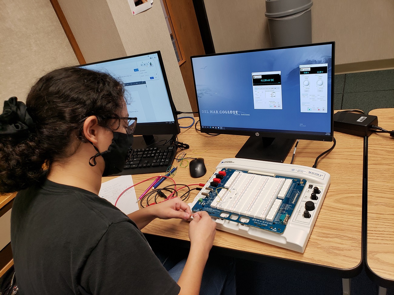 An electrical engineering student is working on a lab in the classroom.