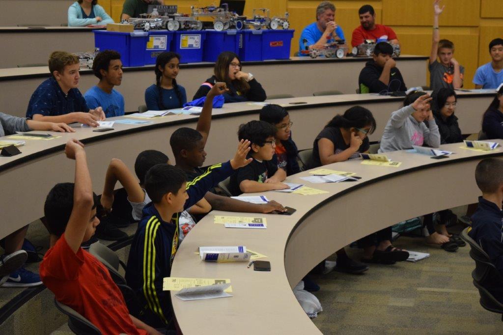 Students raise their hands to answer questions in a classroom