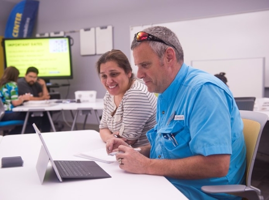 Tutor working with a student that is using a laptop.