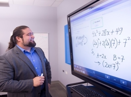A teacher showing math equations on a smartboard. Smiling and happy.