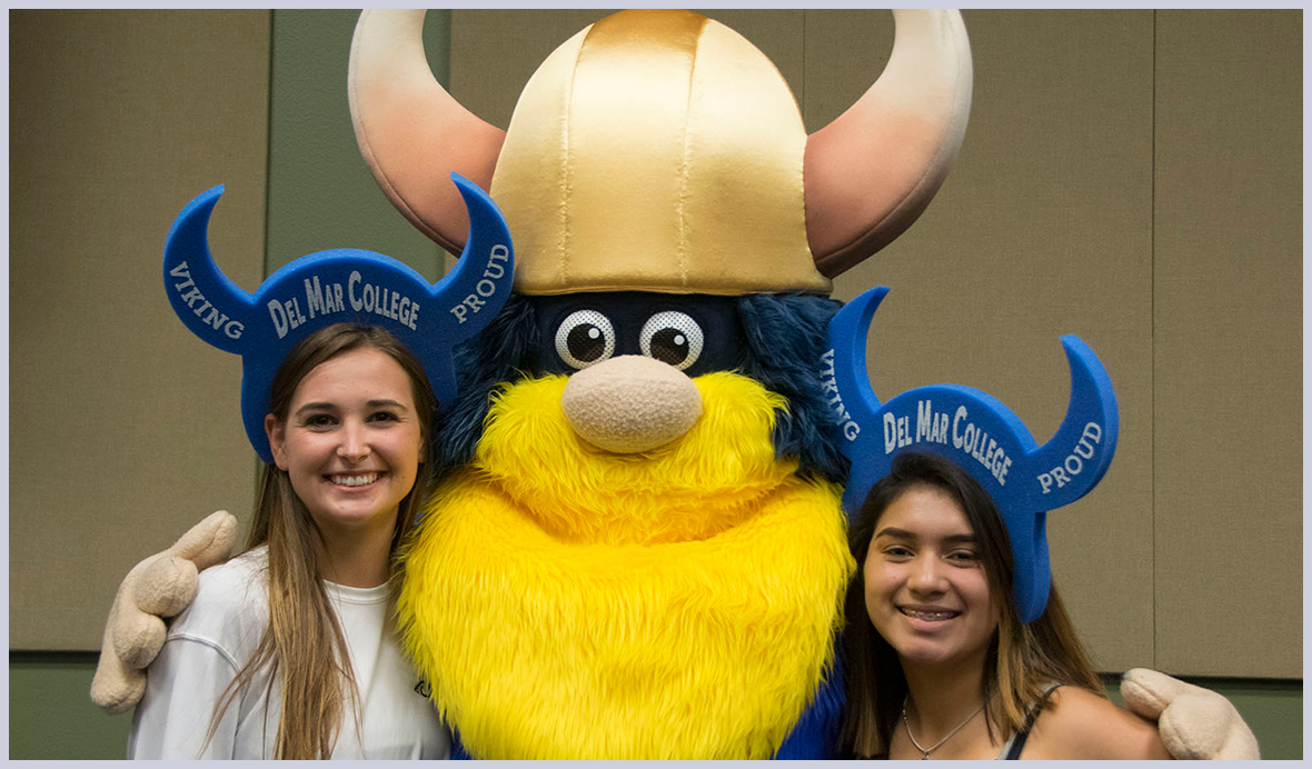 Viking mascot smiles with two students in Viking hats