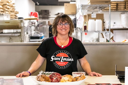 Pizza owner stands in her shop