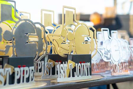 A row of trophies and awards for the Dia De Lost Muertos Welding Competition